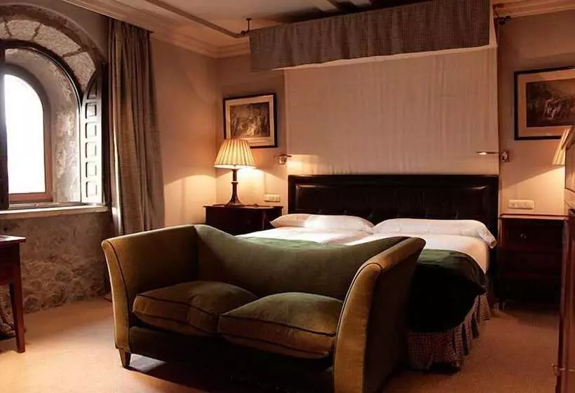 Habitación del Hotel Landa con ventana de arco románico y sillón de terciopelo verde